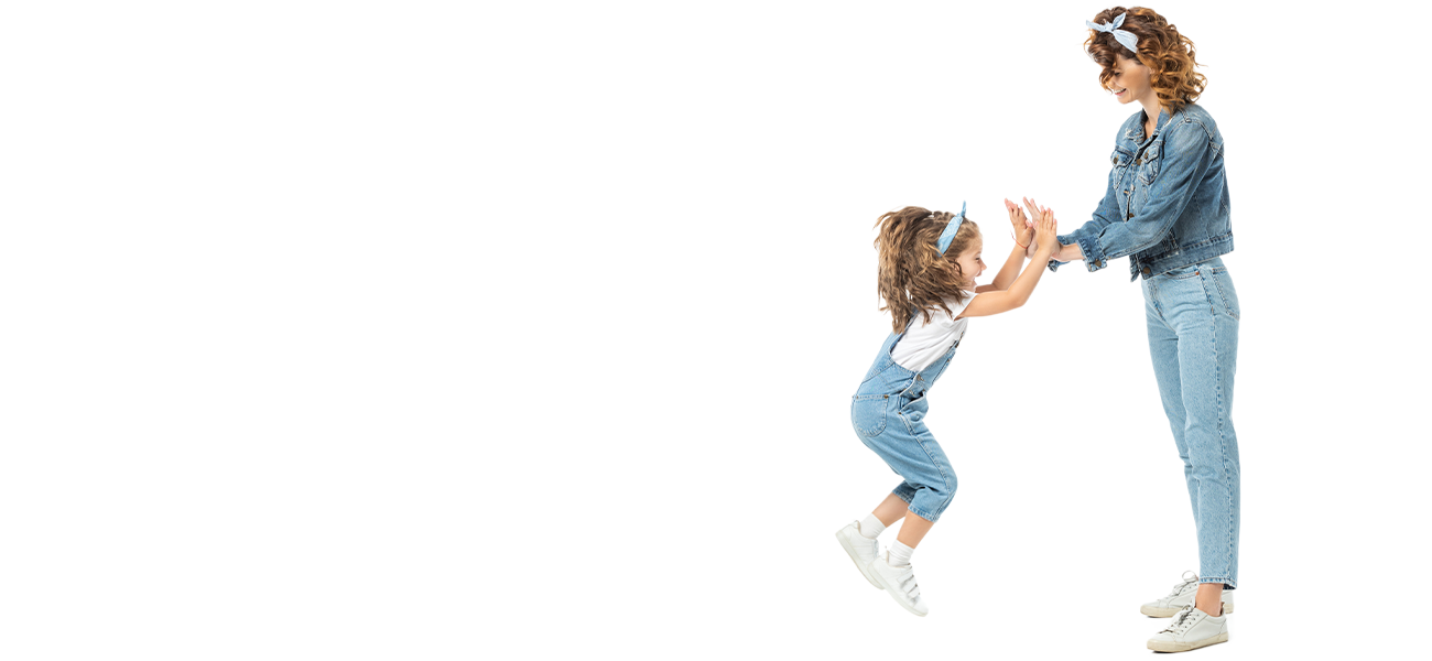A light-skinned woman giving a double high five to a young girl who is jumping in the air. They are wearing matching blue jean outfits.
